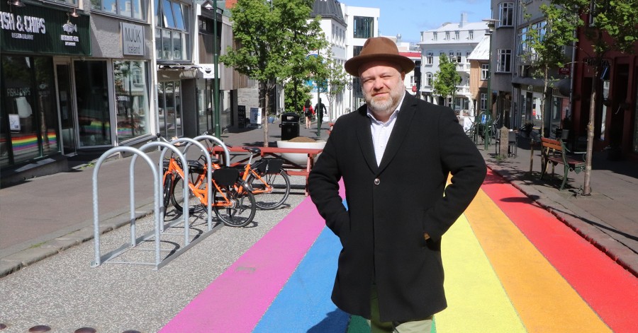 Guðjón Ragnar Jónsson stendur við götu sem er máluð í regnbogalitunum
