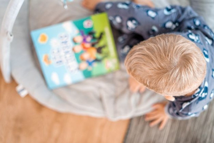 Séð ofan á kollinn á ljóshærðan strák sem er að lesa bók