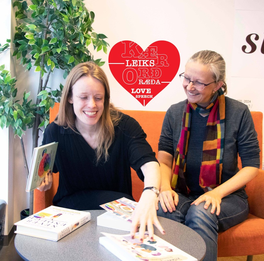 two women smiling and pointing at books